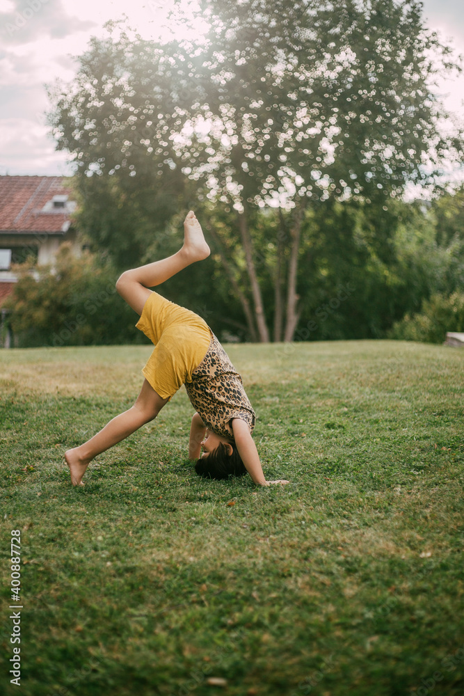 Side view of girl practicing headstand in yard Side view of girl practicing headstand in yard