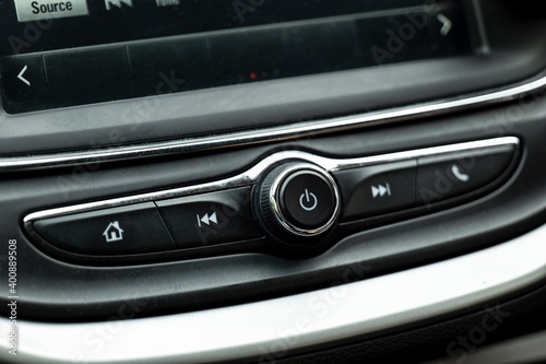 Power button and various controls of a car radio in an interior of modern vehicle