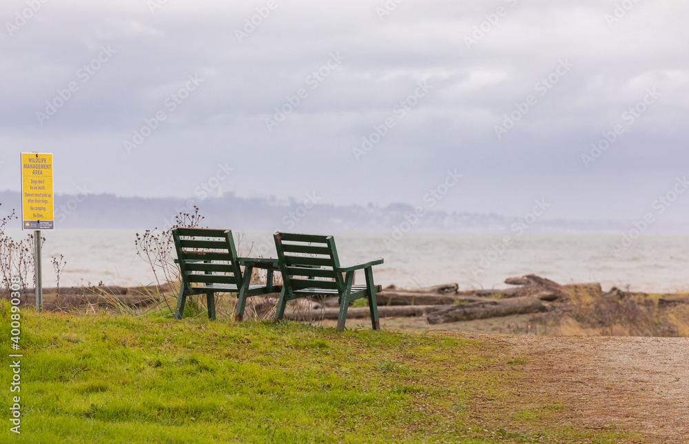Empty benches on the shore of the ocean on a winter cloudy day.