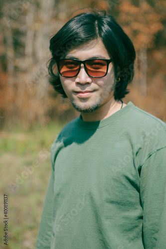 portrait of long hiar asian man with smiling face standing outdoor photo