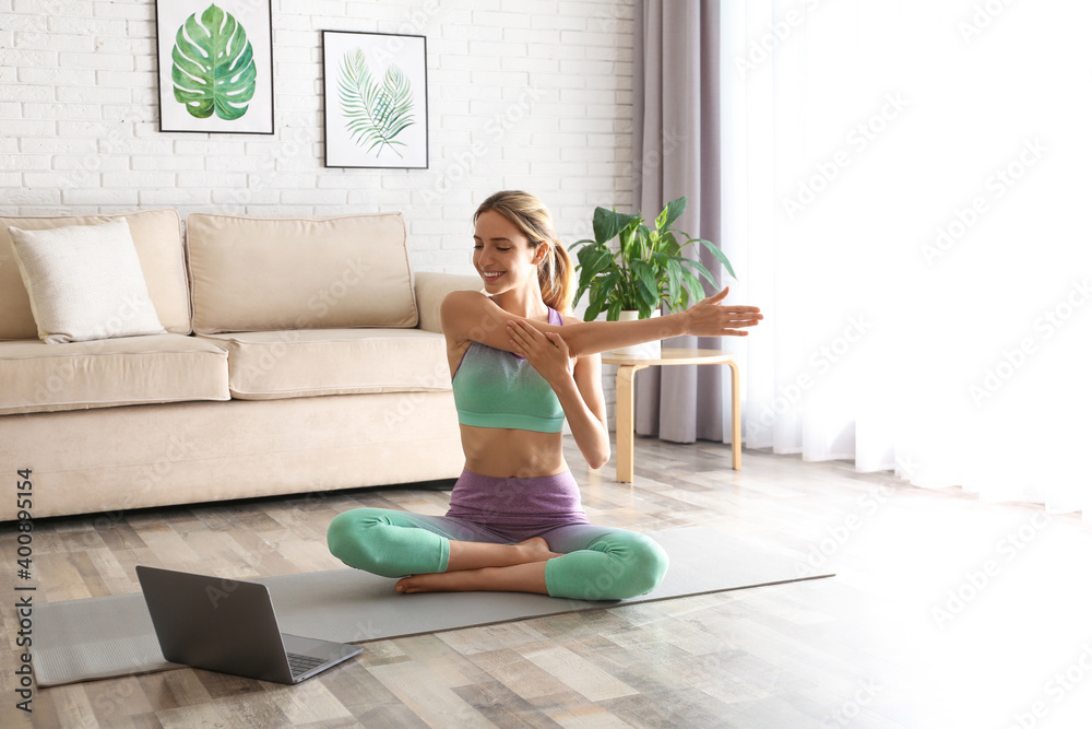 Woman having online video class via laptop at home. Distance yoga course during coronavirus pandemic Woman having online video class via laptop at home. Distance yoga course during coronavirus pandemic