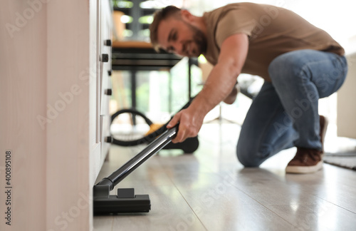 Young man using vacuum cleaner at home