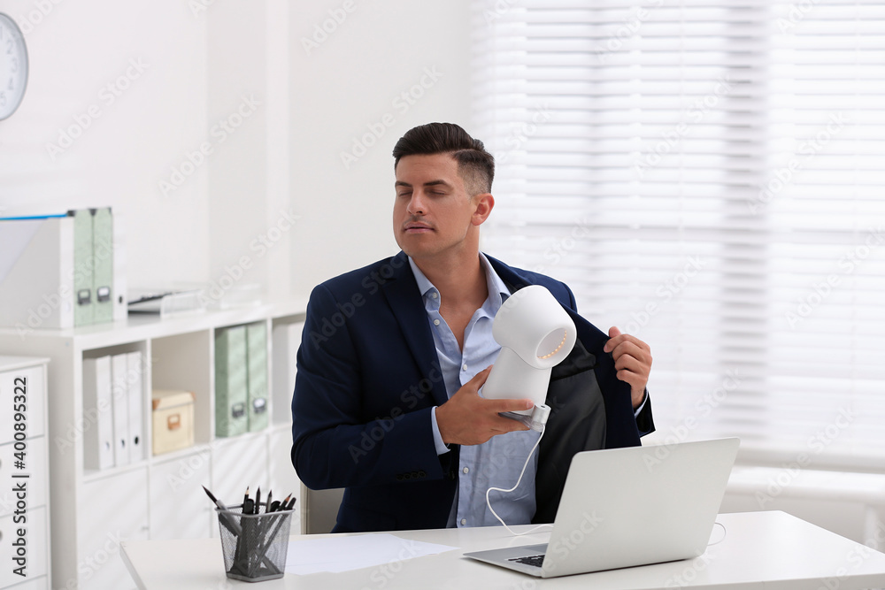 Man enjoying air flow from fan at workplace