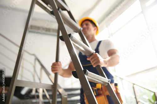 Professional builder with metal ladder on stairs, closeup photo