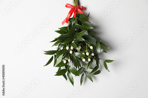 Konstfotografi Mistletoe bunch with red bow hanging on white wall