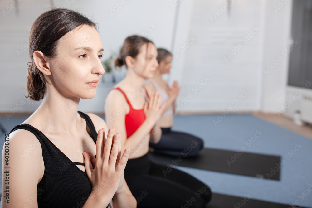Three girls practicing yoga. Yoga instructor with her students meditating in a studio. Three girls practicing yoga. Yoga instructor with her students meditating in a studio.