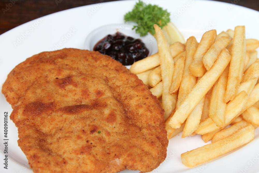 Filled pork schnitzel called Cordon Bleu with French fries, cranberry jam and lemon Filled pork schnitzel called Cordon Bleu with French fries, cranberry jam and lemon