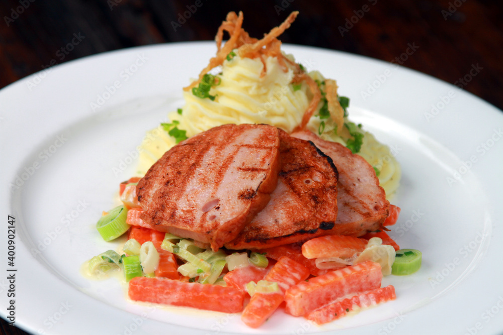 Roasted slices of pork loaf with creamy carrots and leek, served with potato mash and fried onions