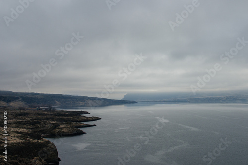 Wallpaper Mural A beautiful foggy landscape in a blue-gray scale: a wide river, in front of the horizon are dark blue mountains, on the banks of the hills with dry grass. Colorado river, OR, USA Torontodigital.ca