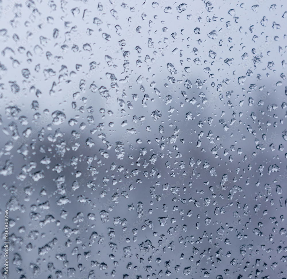 Melting snow on the glass, drops of water condensation on the window, and transparent glass of the window in cold winter, winter landscape outside the window, close-up.