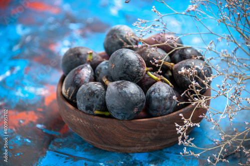 Front close view of black mission figs in of a small brown pot on blue table photo