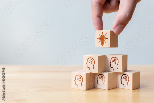 Concept creative idea and innovation. Hand picked wooden cube block with head human symbol and light bulb icon photo