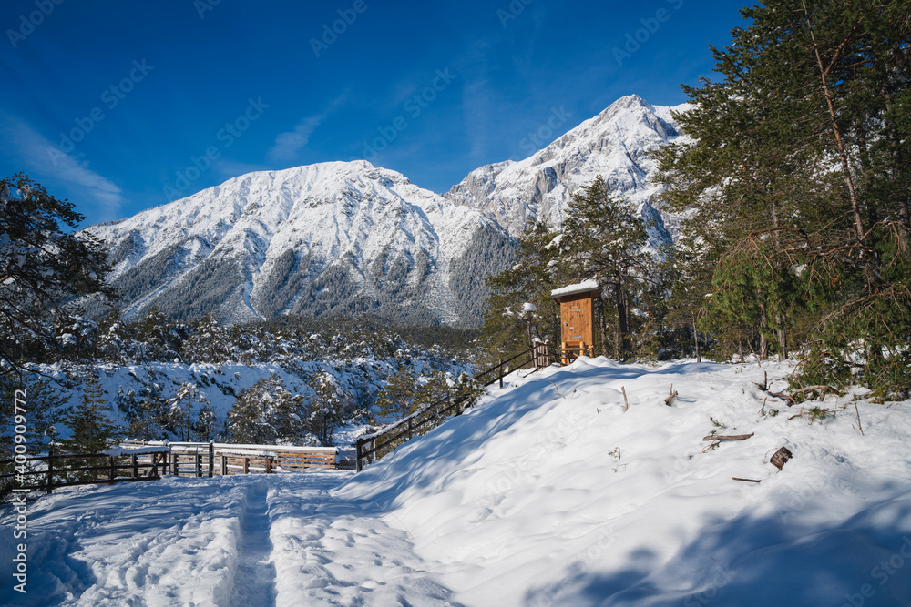 Small winter walking path through snow over bridge in Austrian Alps at Mieming, Tyrol, Austria Small winter walking path through snow over bridge in Austrian Alps at Mieming, Tyrol, Austria