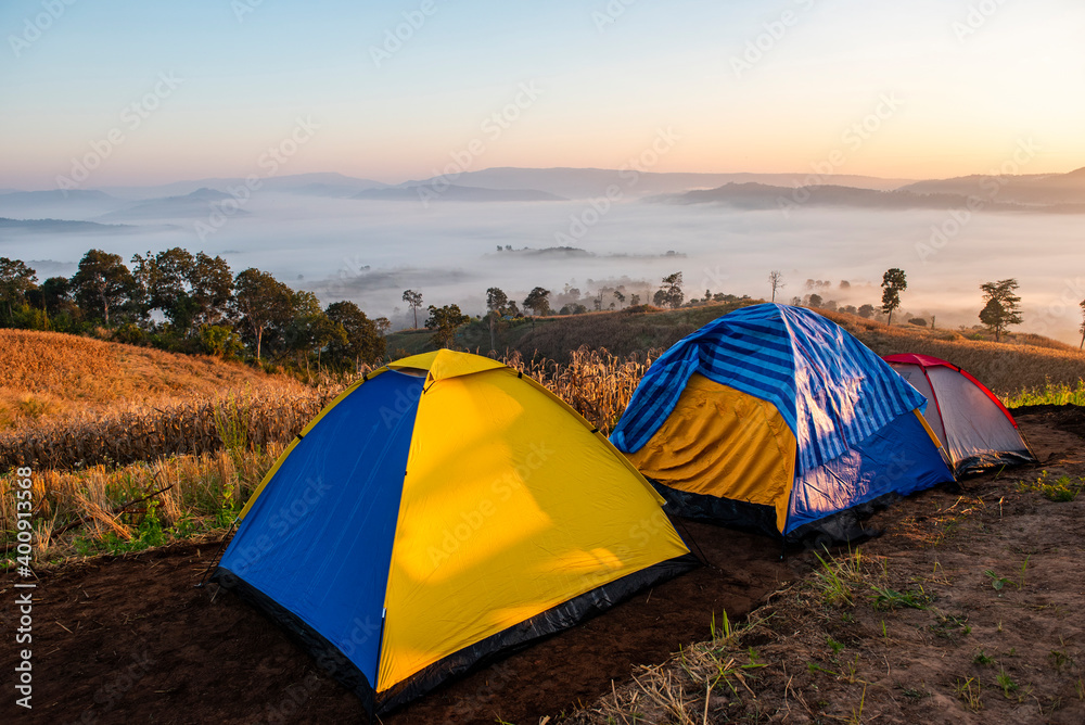 Camping tent area on mountain, tourist tent camping with fog mist landscape sunrise beautiful in winter view outdoor travel.