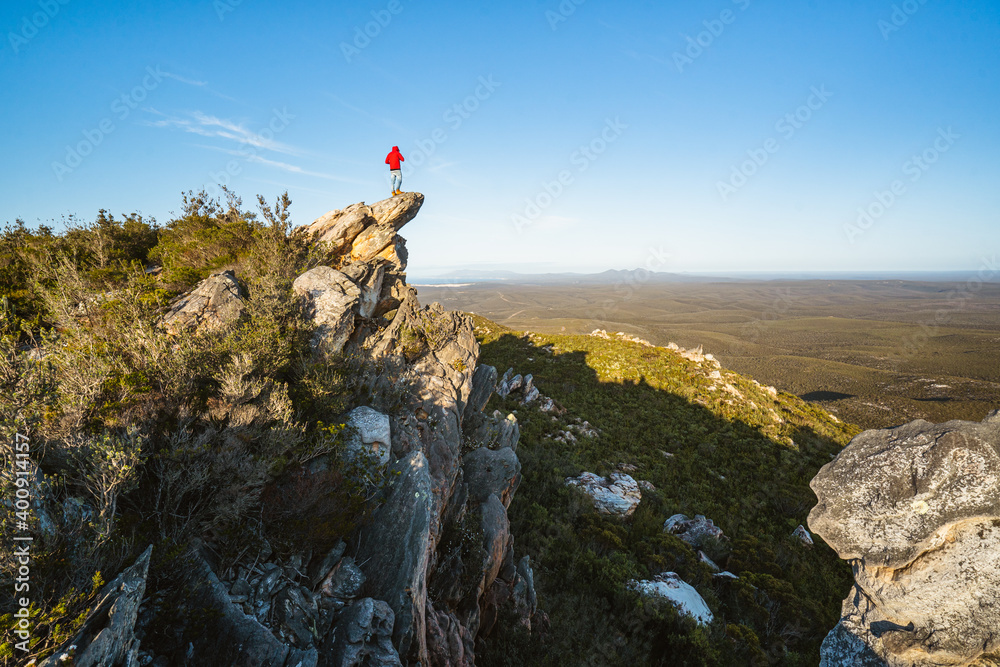 Lone man standing on the top of East Mount Barren as the sun rises behind him. Located in the Fitzgerald River National Park in Hopetoun, Western Australia. 