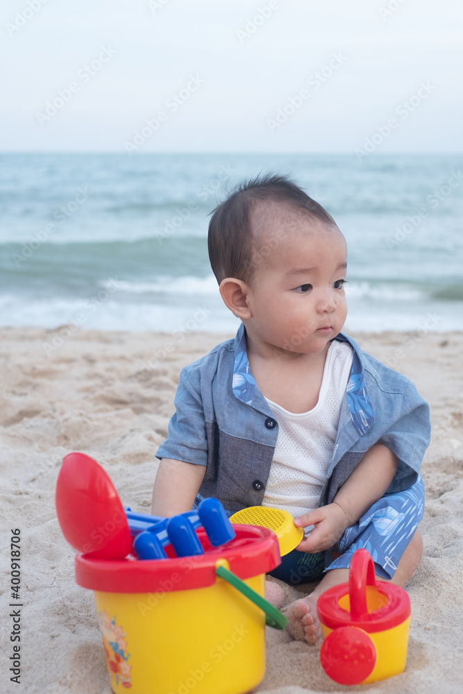 Adorable Cute Asian baby boy playing with beach toys on tropical beach Adorable Cute Asian baby boy playing with beach toys on tropical beach