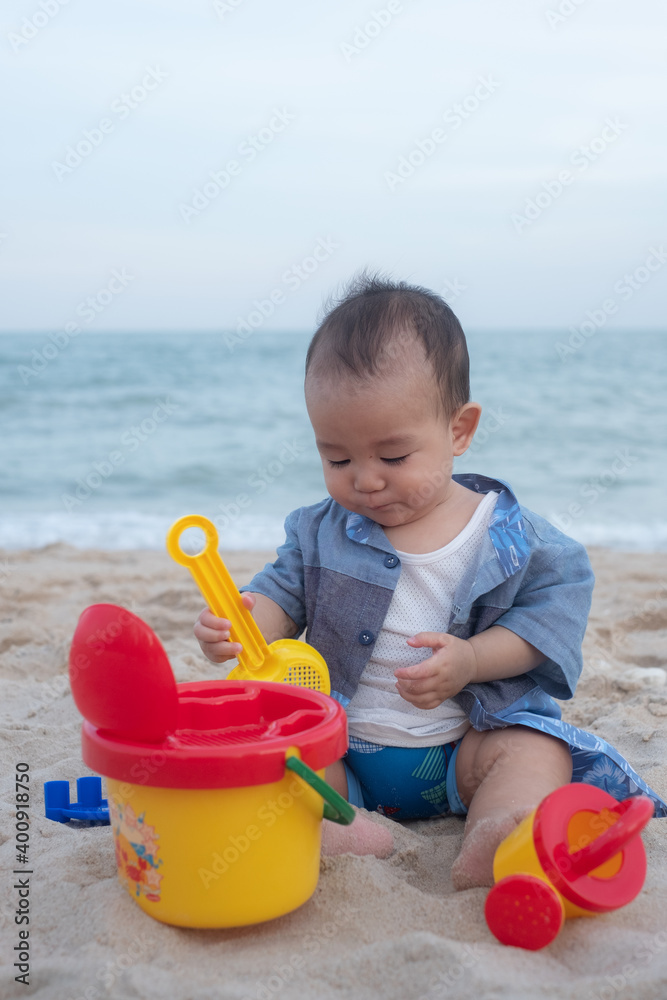 Adorable Cute Asian baby boy playing with beach toys on tropical beach Adorable Cute Asian baby boy playing with beach toys on tropical beach