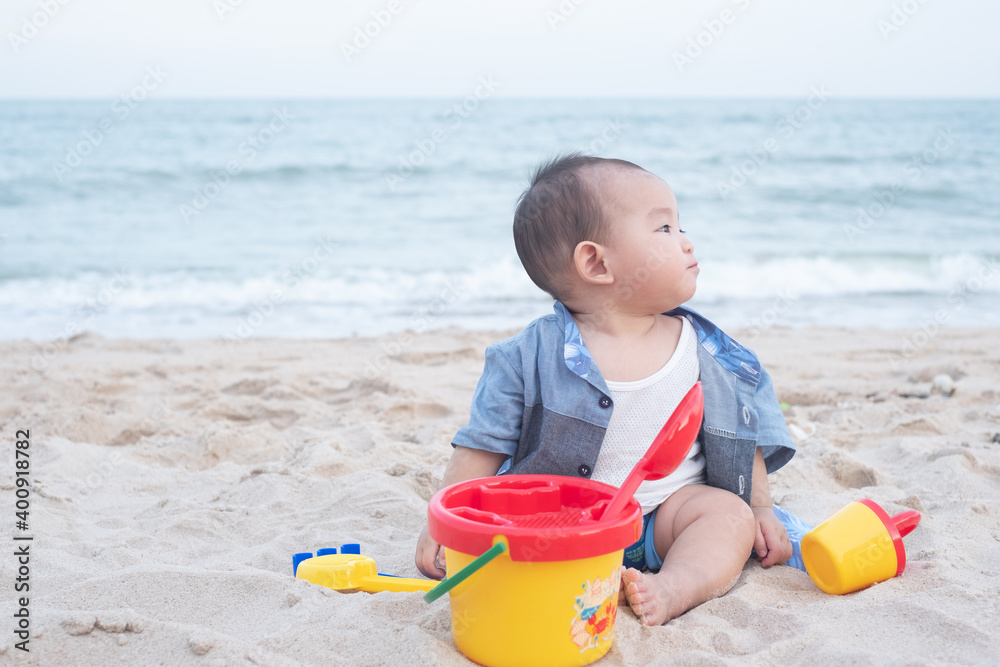Adorable Cute Asian baby boy playing with beach toys on tropical beach Adorable Cute Asian baby boy playing with beach toys on tropical beach