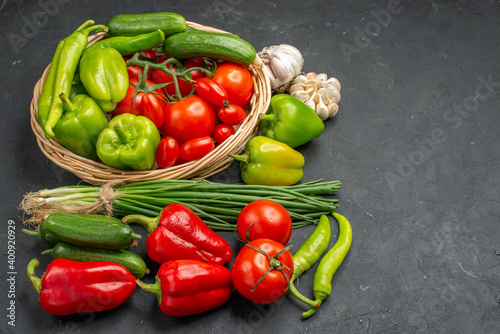 Side view of fresh various organic vegetables in wicker basket on dark background