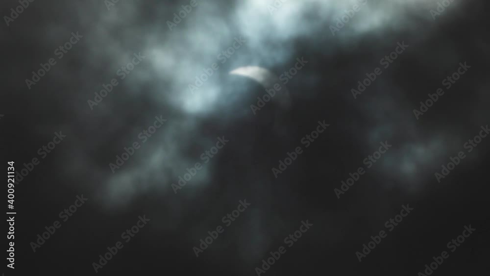 Dark clouds moving in front the moon shadow covered sun, a solar eclipse, in raw daylight Dark clouds moving in front the moon shadow covered sun, a solar eclipse, in raw daylight