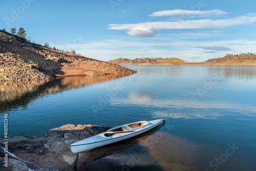 decked expedition canoe on a rocky shore of a mountain lake - Horsetooth Reservoir in northern Colorado in fall or winter scenery