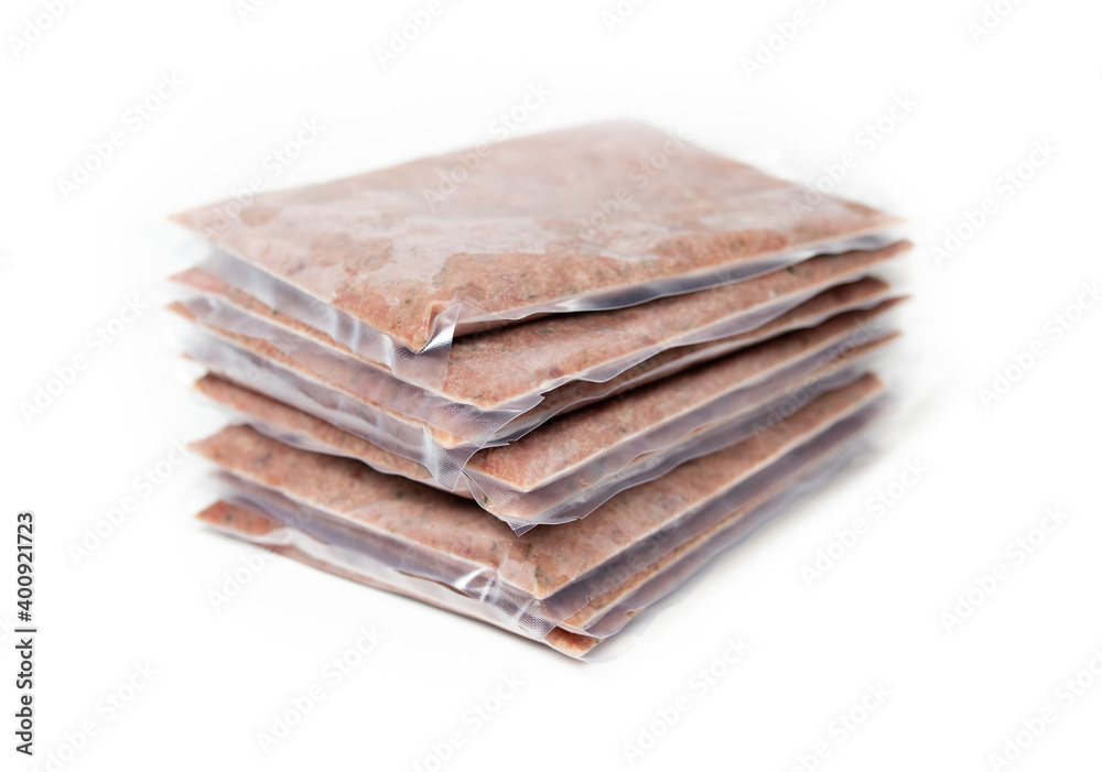 Pile of raw frozen meat packages vacuum sealed, perspective view. Ground turkey inclusive backs, necks, liver and heart. Concept for raw food diet for cats, dogs and pets. Selective focus. Pile of raw frozen meat packages vacuum sealed, perspective view. Ground turkey inclusive backs, necks, liver and heart. Concept for raw food diet for cats, dogs and pets. Selective focus.