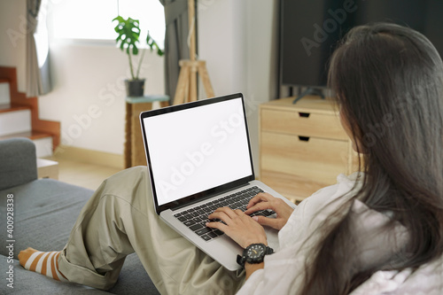 Side View shot of young business woman working with mockup white screen laptop computer in living room at her home. Working at home concept