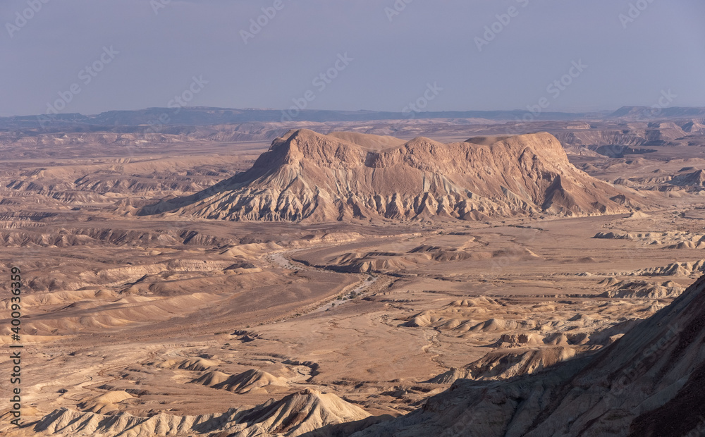 Fototapeta premium Majestic mountain range in a remote part of Negev desert, Israel. Panoramic landscape of dry wadies, colorful sandy hills, mountain folds and rock formations. The harsh beauty of the desert.
