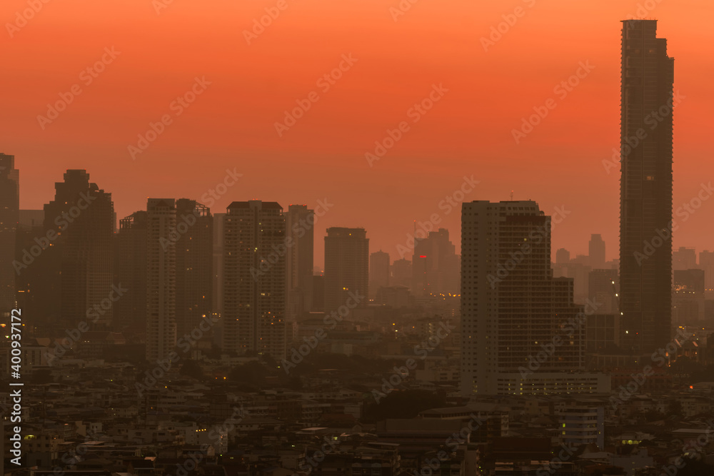 Air pollution in Bangkok, Thailand. Smog and fine dust of pm2.5 covered city in the morning with orange sunrise sky. Cityscape with polluted air. Dirty environment. Urban toxic dust. Unhealthy air.