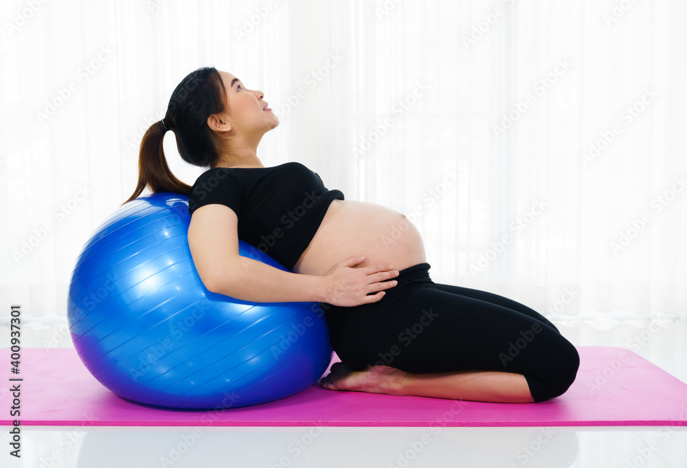 Fototapeta premium pregnant woman doing yoga exercise on fitness ball in living room at home