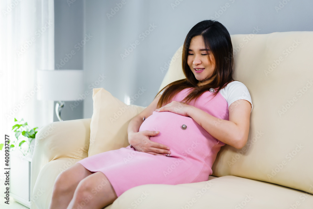 pregnant woman stroking her belly on sofa in living room pregnant woman stroking her belly on sofa in living room
