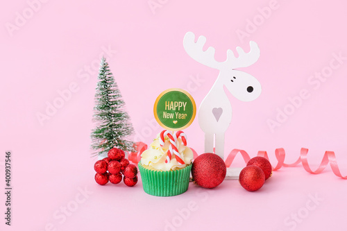 Tasty Christmas cupcake and decor on color background