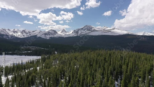 High Definition Aerial Video flying over evergreen forest and frozen lake in Colorado.