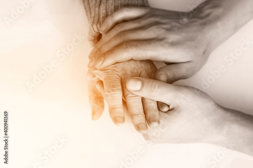 Handshake, caring, trust, treatment and support. The hand of a young doctor holds the hand of an elderly woman, or he checks the comma to see how the bones have grown together. Medicine and healthcare