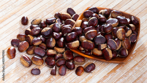 Unpeeled edible sweet chestnuts on wooden background, cooking ingredients