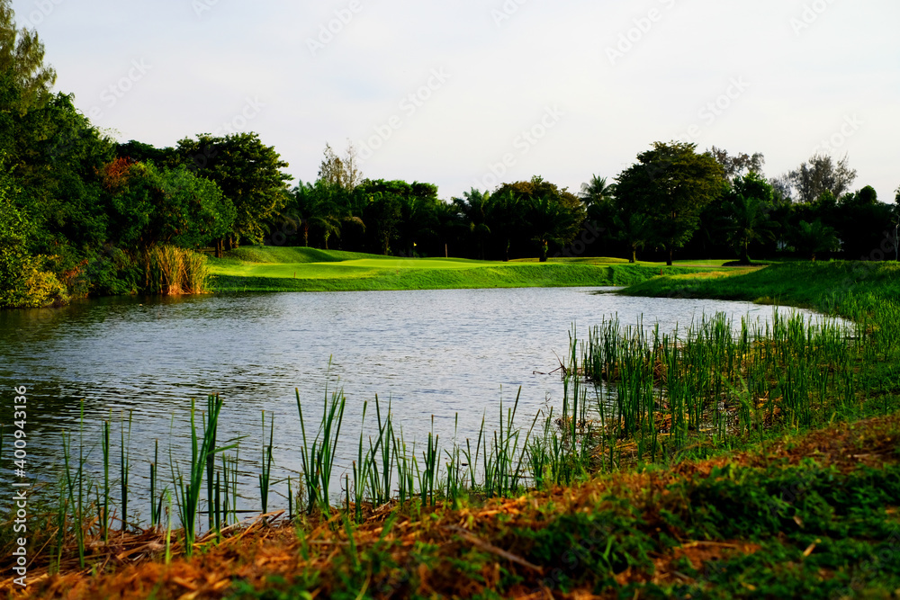 A pond with greenery trees and golf fairway on mountain and blue sky background 6