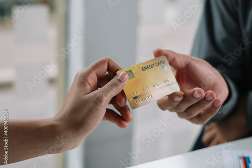 woman passing a payment credit card to the seller. Girl holding a credit card. Shallow depth of field with focus on women hand