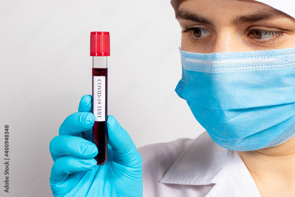 A doctor or lab technician wearing a mask and gloves is holding a blood test tube with the inscription coronavirus test. COVID-19 Diagnostics, Rapid Test, SARS-CoV-2 Virus Detection A doctor or lab technician wearing a mask and gloves is holding a blood test tube with the inscription coronavirus test. COVID-19 Diagnostics, Rapid Test, SARS-CoV-2 Virus Detection