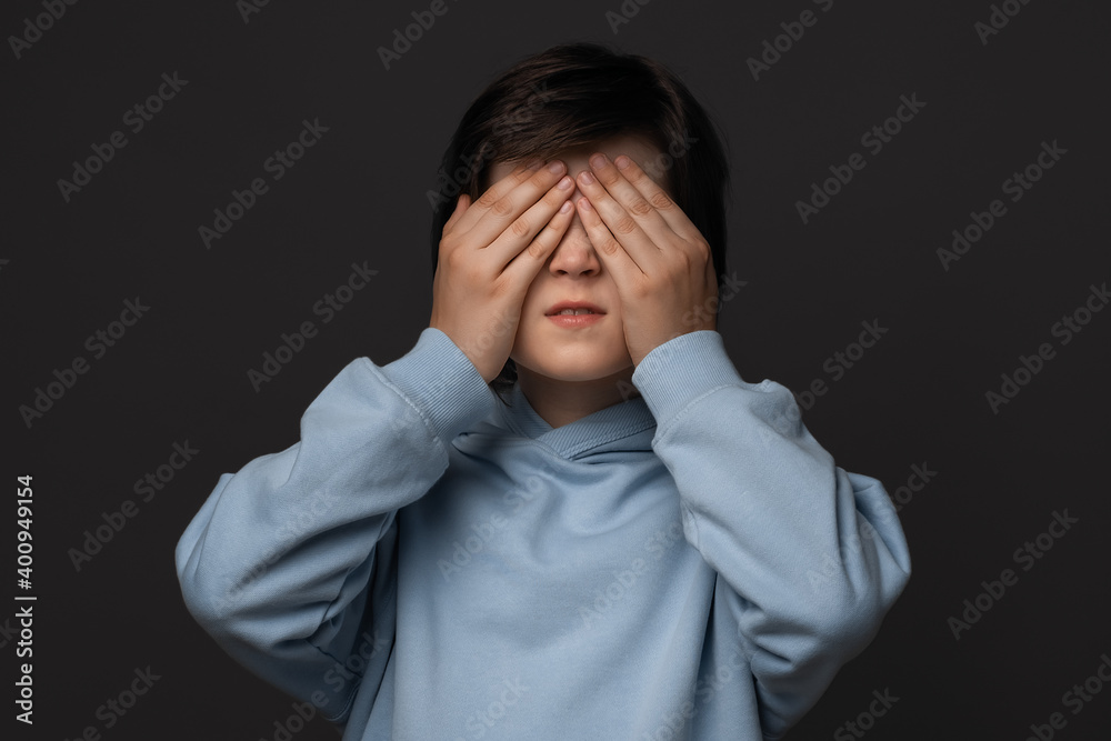 Portrait of boy 10-12 years old covering his eyes with hands. Facial expression concept. Studio shot, white background Portrait of boy 10-12 years old covering his eyes with hands. Facial expression concept. Studio shot, white background