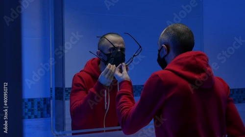 a man in the toilet takes off his glasses a mask from the coronavirus photo