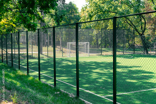 Soccer field behind the iron fence. School soccer stadium