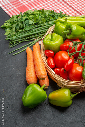 Vertical view of fresh various organic vegetables in a wooden basket on orange stripped towel on dark background