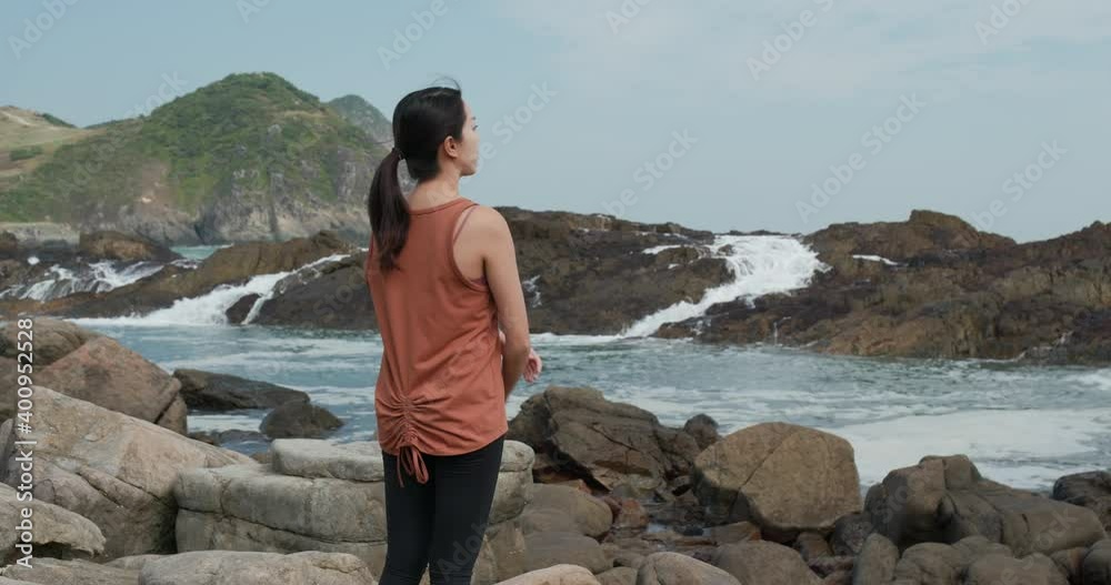 Woman look at the sea wave over the rock Woman look at the sea wave over the rock