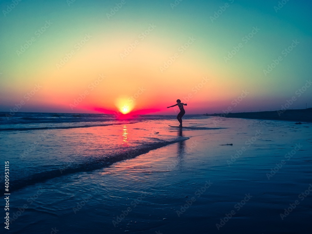 Boy skimming on the beach during sunset 