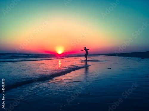 Boy skimming on the beach during sunset 
