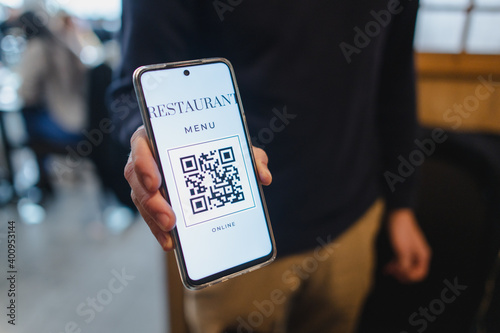 Close-up man hand holding smartphone showing QR code. Restaurant menu online. New normal concept.