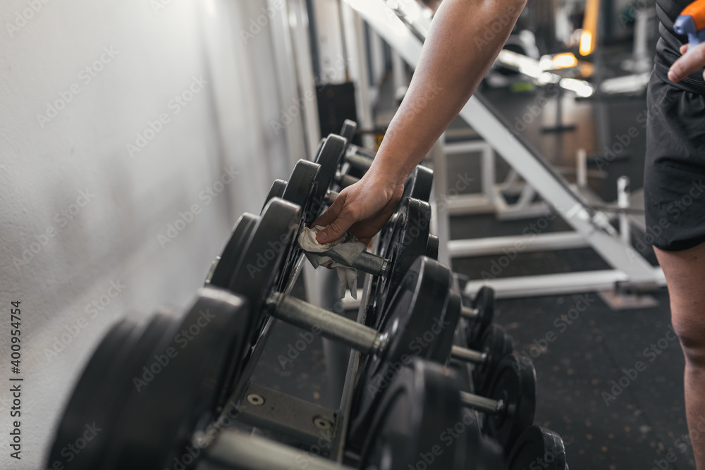 Close-up of the athlete with paper disinfecting the weights in the gym. Covid19. . Covid-19. Concept of health and sport. Close-up of the athlete with paper disinfecting the weights in the gym. Covid19. . Covid-19. Concept of health and sport.
