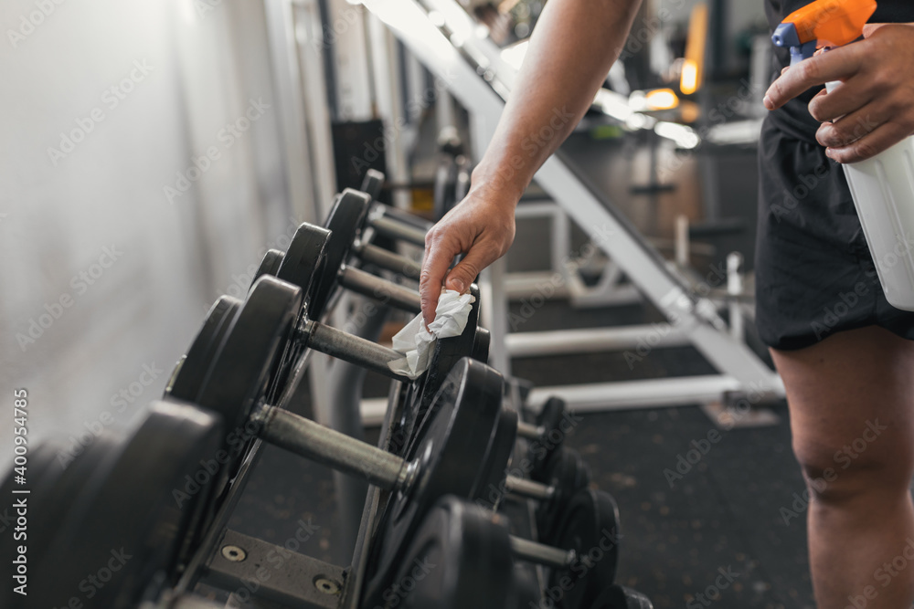 Close-up of the athlete with paper disinfecting the weights in the gym. Covid19. . Covid-19. Concept of health and sport. Close-up of the athlete with paper disinfecting the weights in the gym. Covid19. . Covid-19. Concept of health and sport.