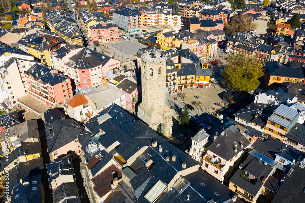 Scenic aerial view of residential areas in small Spanish town of Puigcerda with domineering tower of medieval church of Santa Maria, Catalonia