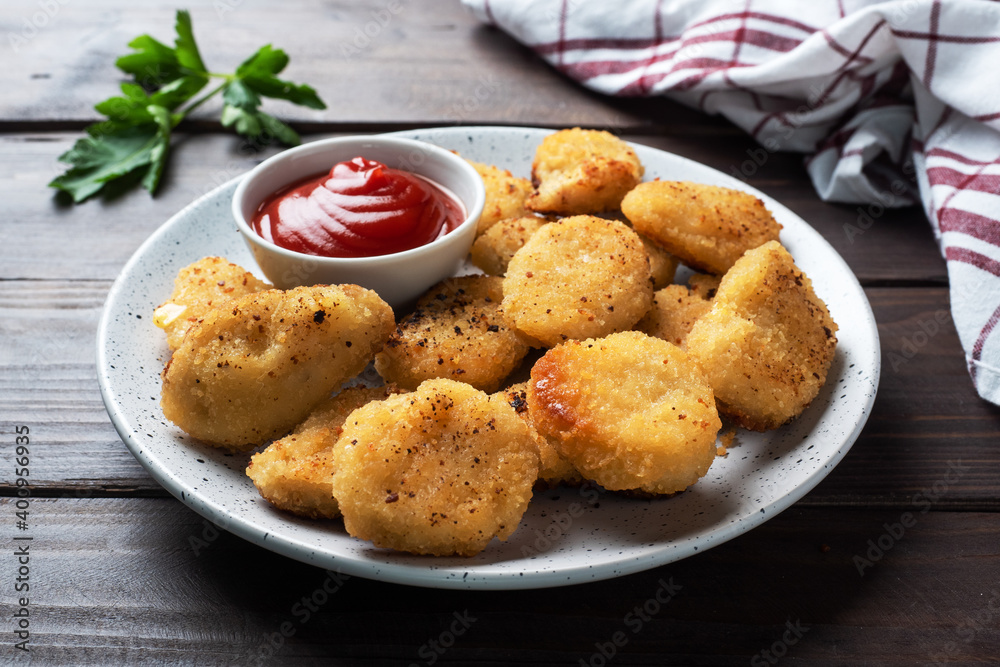 Fried chicken nuggets with tomato ketchup sauce. Wooden background. Copy space.